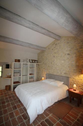 une chambre avec un grand lit et un mur en pierre dans l'établissement DOMAINE de MAS CARON Gîte 4* au pied du Ventoux en Provence, à Caromb
