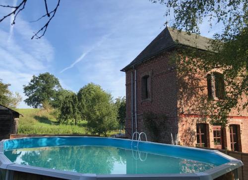une piscine devant un bâtiment en briques dans l'établissement Stunning 5 bedroom French Manor house, Normandy, à Beaunay