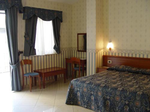 a hotel room with a bed and a table and chairs at Hotel Kroma in Ragusa