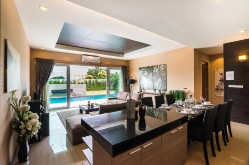 a living room with a dining room table and chairs at The Ville Jomtien Pool Villa in Jomtien Beach