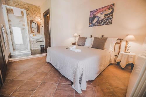 1 Schlafzimmer mit einem weißen Bett und einem Badezimmer in der Unterkunft Residenza Storica le Civette in Castel del Monte