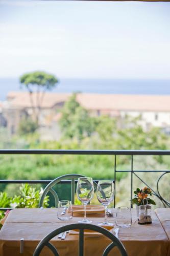 a wooden table with wine glasses on a balcony at Hotel La Primavera in Massa Lubrense