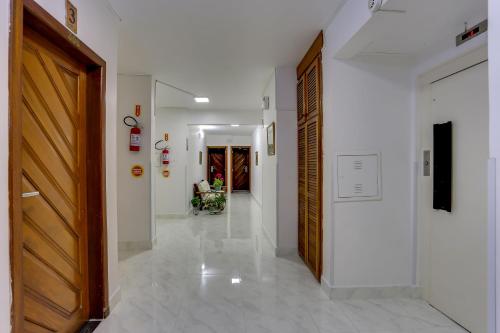 a hallway with white walls and a wooden door at Hotel Vila Mar in Florianópolis