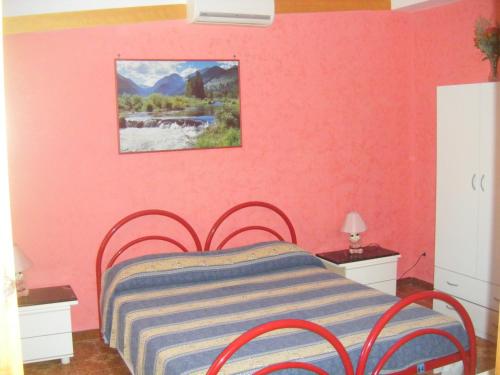 ein Schlafzimmer mit einem Bett mit einer rosa Wand in der Unterkunft Villa Robinia in Massafra