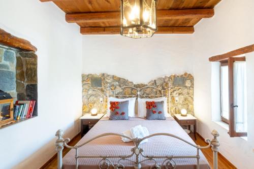 1 dormitorio con 1 cama con pared de piedra en Villa Maria, en Stavrokhórion