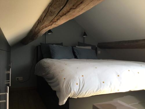 a bedroom with a bed with white sheets and blue pillows at L’Aragne in Dinant