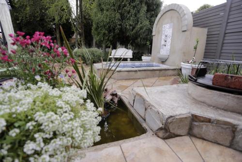 a garden with a pond and flowers and a bench at A La Maison Boutique Guesthouse in Parys