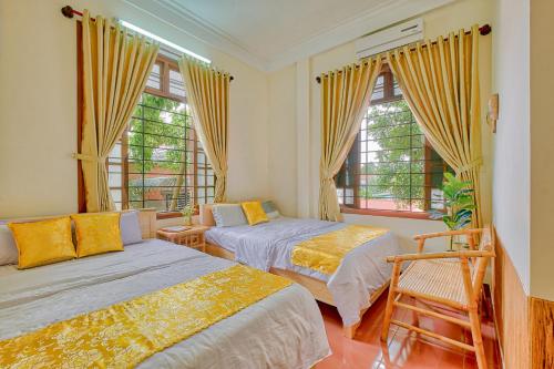a bedroom with two beds and two windows at Le Robinet Homestay in Hue