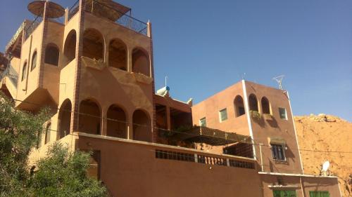 a building in the desert with a mountain in the background at Auberge Des Jardins du Dades in Boumalne