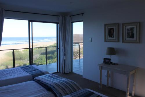 a bedroom with two beds and a balcony with the ocean at Oyster bay beach house in Oyster Bay