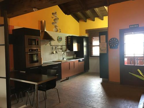 cocina con mesa y paredes de color negro y naranja en CASA RURAL ANTONIO, en Martiherrero