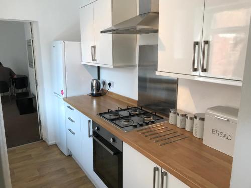 a kitchen with white cabinets and a stove top oven at Warwick Street Professional Lets in Newcastle upon Tyne
