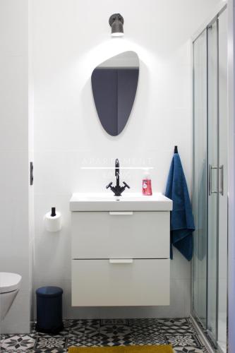 a white bathroom with a sink and a mirror at Apartament KOSMOS z miejscem parkingowym in Toruń
