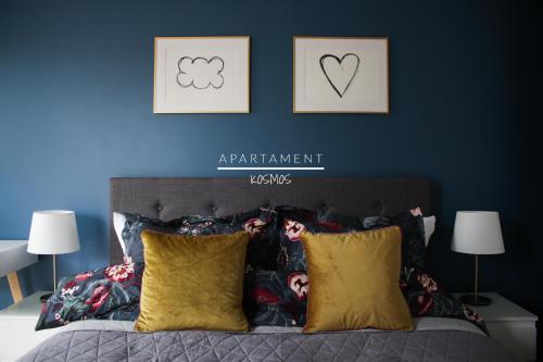 een slaapkamer met een blauwe muur en een bed met kussens bij Apartament KOSMOS in Toruń