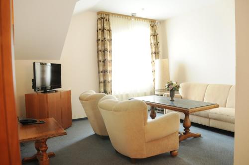 ein Wohnzimmer mit einem Sofa, einem Tisch und einem TV in der Unterkunft Amicus Hotel in Vilnius