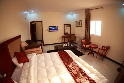 a bedroom with a large bed and a living room at Fakher Yanbu Hotel in Yanbu
