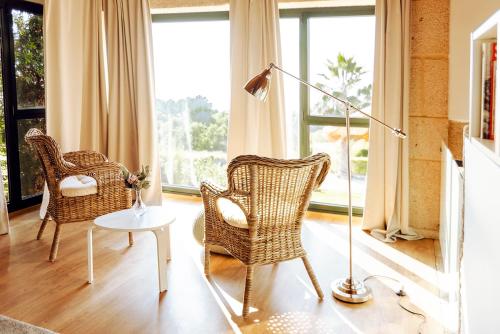 two wicker chairs and a lamp in a living room at Bosque de Xarás, casa completa con encanto cerca de playa de Lapamán in Marín