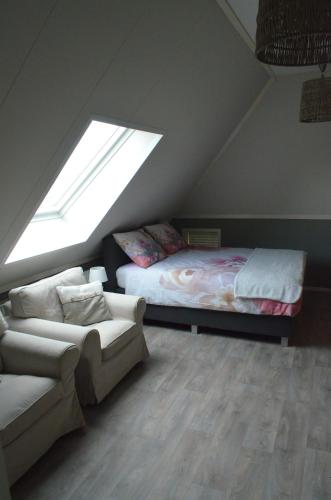a attic room with a bed and a couch at B&B “de Boerlarij” in Ruinerwold