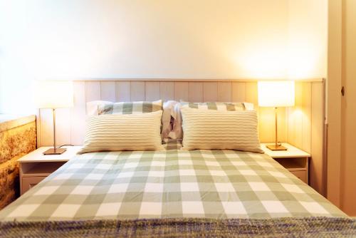 a bedroom with a checkered bed with two lamps at Bosque de Xarás, casa completa con encanto cerca de playa de Lapamán in Marín