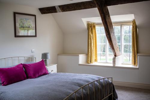 a bedroom with a bed with purple pillows and a window at West Cottage, Cerne Abbas Lane in Dorchester
