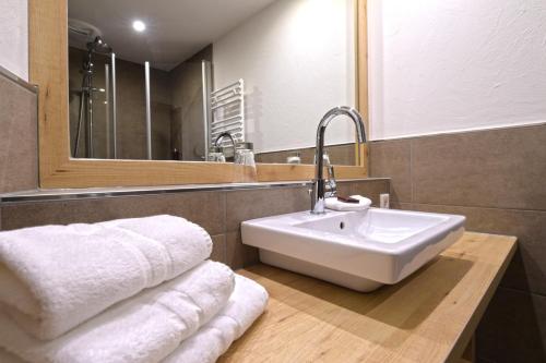 ein Badezimmer mit einem Waschbecken, einem Spiegel und Handtüchern in der Unterkunft Hotel Hennemann in Cobbenrode