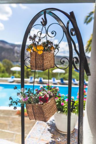 two baskets of flowers hanging from a wrought iron fence at Villa dei Sogni in Vulcano