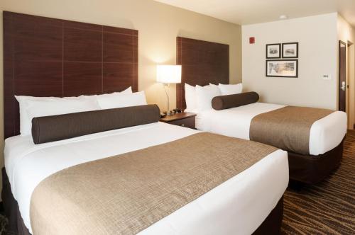 two beds in a hotel room with two beds at Cobblestone Hotel & Suites Appleton International Airport in Neenah