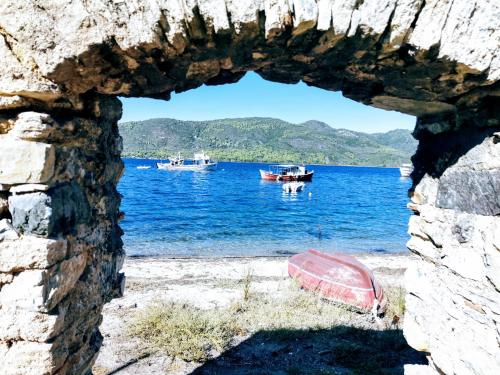 a window in a stone wall with boats in the water at Hotel Rania in Loutra Edipsou