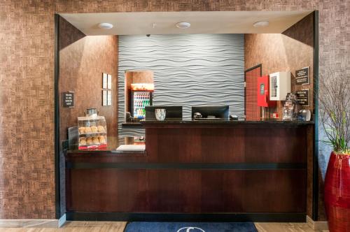 a lobby of a hotel with a mirror above a counter at Cobblestone Hotel & Suites Appleton International Airport in Neenah