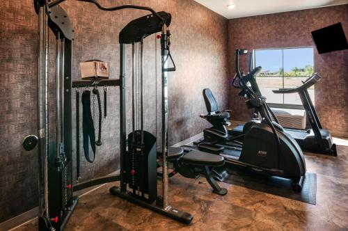 a gym with a treadmill and elliptical machines in a room at Cobblestone Hotel & Suites Appleton International Airport in Neenah