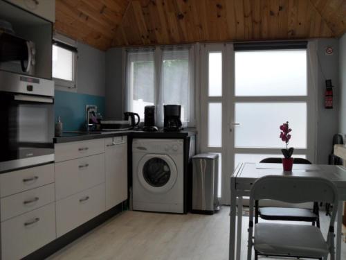 uma cozinha com uma máquina de lavar roupa e uma mesa em Meublé classé 3 étoiles em Saint-Brieuc