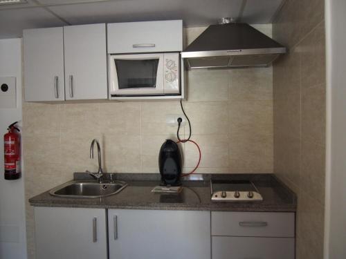 una pequeña cocina con fregadero y microondas en Apartamentos Las Dunas de Levante, en Es Pujols