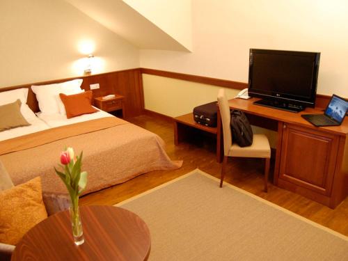 a hotel room with a bed and a desk with a computer at Trifecta Udvarház in Tállya