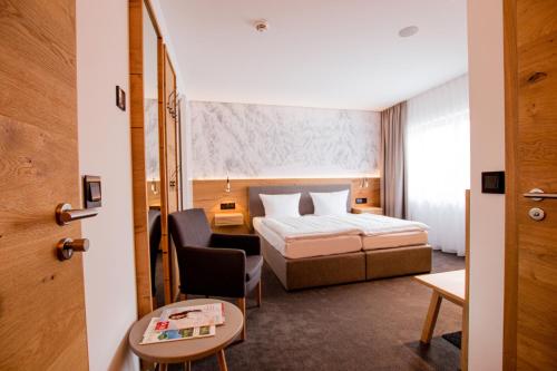 une chambre d'hôtel avec un lit et une chaise dans l'établissement Hotel Tannenhaus, à Schöneck