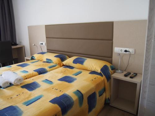twee bedden in een kamer met gele en blauwe lakens bij Apartamentos Las Dunas de Levante in Es Pujols