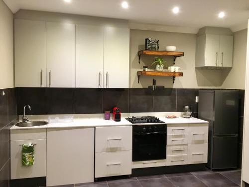 a kitchen with white cabinets and a black refrigerator at The Cottage 60 on 21st Avenue in Mossel Bay