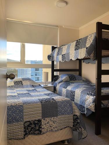 two bunk beds in a room with a window at Papudo Laguna Apartment in Papudo