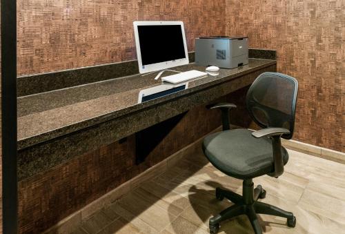a desk with a computer monitor and a chair at Cobblestone Hotel & Suites Appleton International Airport in Neenah