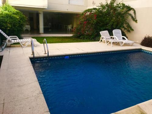 una piscina con 2 sillas de césped y 2 sillas de jardín en Confortable departamento. Excelente ubicación en Buenos Aires