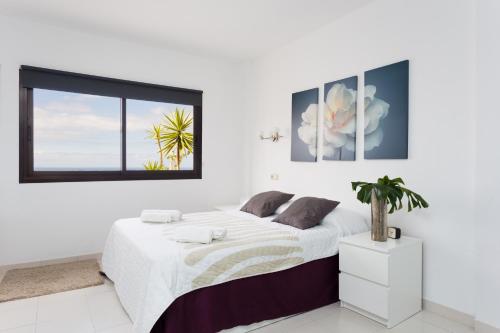 a white bedroom with a large bed and a window at Apartment Paradise Court in Adeje