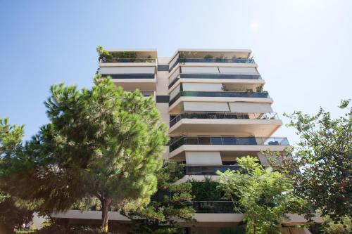 un edificio de apartamentos alto con árboles delante de él en Homz Studios Faliro en Athens