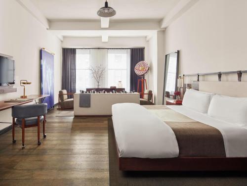 ニューヨークにあるリファイナリー ホテル ニューヨークのベッドとリビングルームが備わるホテルルームです。