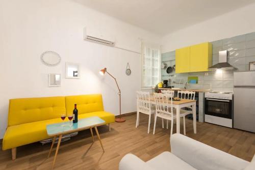 een woonkamer met een gele bank en een keuken bij Saint Dimitrios Central Apartment 100sqm. in Thessaloniki