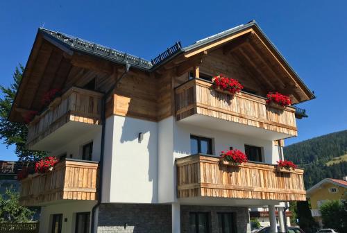 a building with wooden balconies and red flowers on it at Appartementhaus Sky Lodge in Altenmarkt im Pongau
