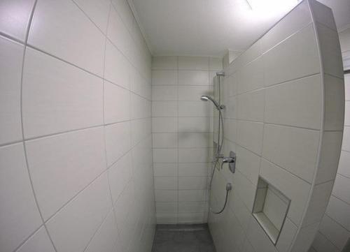 a white tiled bathroom with a shower stall at Pension Kochertal in Aalen