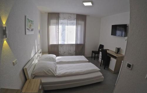a bedroom with two beds and a desk and a window at Pension Kochertal in Aalen