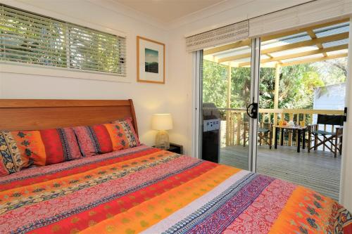 a bedroom with a bed and a balcony with a table at SPINNAKER 1 in Elizabeth Beach