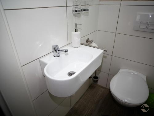 ein Badezimmer mit einem weißen Waschbecken und einem WC in der Unterkunft Bianca`s Hotel Restaurant in Lörrach