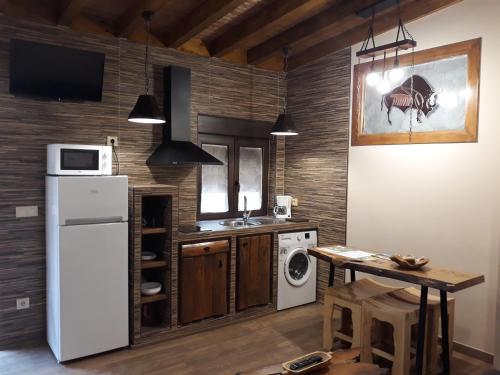 a kitchen with a white refrigerator and a table at Las Cavernas Del Bisonte in Santillana del Mar