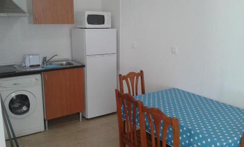 a small kitchen with a table and a white refrigerator at Casa Almeida in Vimieiro